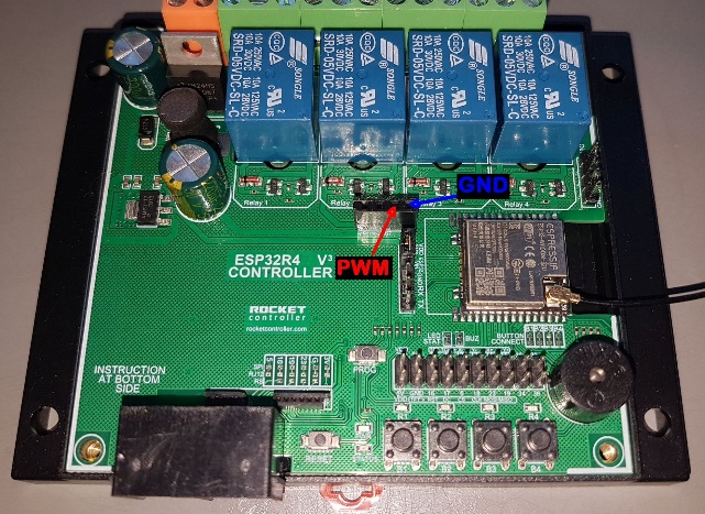 A green circuit board with blue and red buttons
Description automatically generated